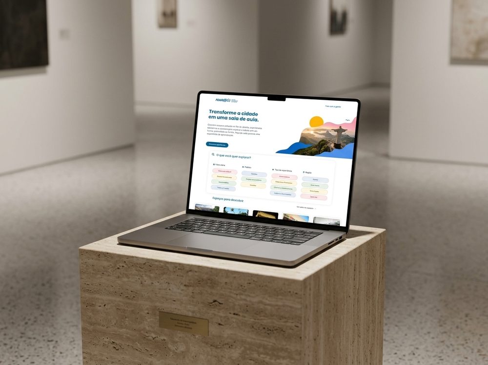 Mockup do site Mundaréu exibido na tela de um notebook sobre pedestal em uma galeria de arte contemporânea.