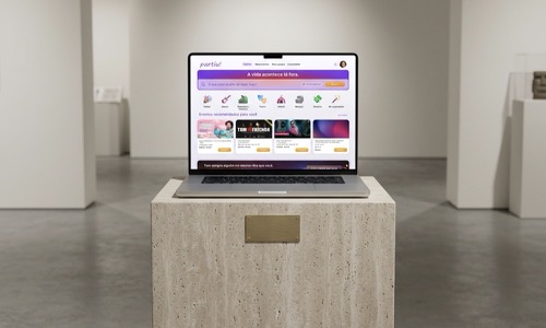 Mockup da plataforma cultural partiu! em notebook sobre pedestal em galeria de arte contemporânea.